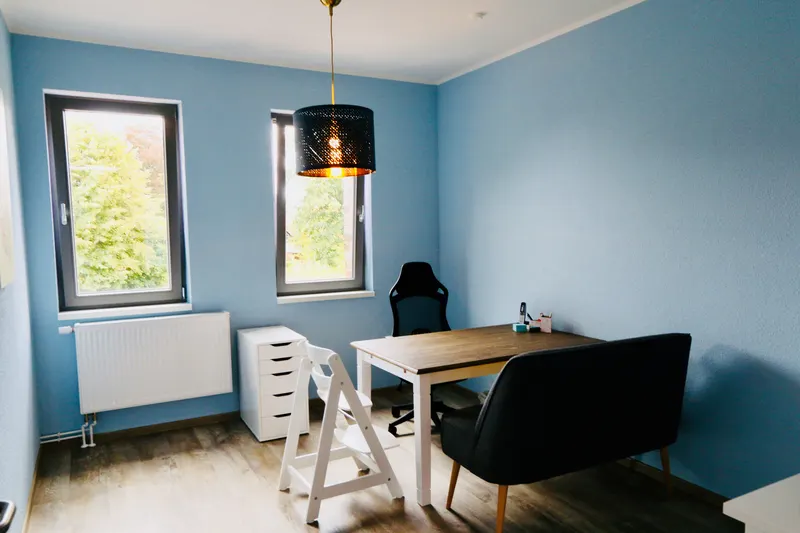 Behandlungszimmer mit blauen Wänden, Schreibtisch und Sesseln