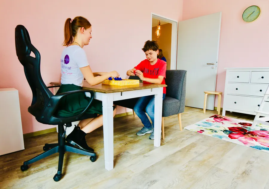 Therapeutin und Kind spielen gemeinsam ein Spiel am Tisch